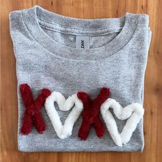 two red and white hearts are placed on top of a gray shirt that says xoxo