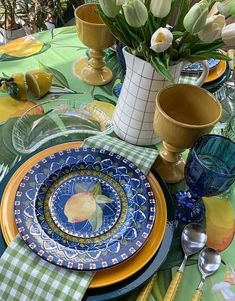 a table set with plates, cups and vases filled with flowers on top of it