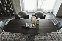 a table with chairs and a vase on it in front of a book shelf filled with books