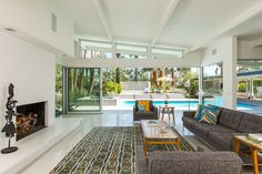 a living room filled with furniture and a fire place in front of a swimming pool