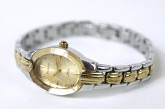 This vintage ARMITRON Women's Quartz Wrist Watch has a watch crystal with a faceted edge.  The watch case is oval, measuring .75" wide and 1" high.  The watch dial is gold tone and barred arrows mark the quarter hours.  The remaining hours are marked with dots.  The hour, minute and second hands are in gold tone.  The bracelet band is two toned in silver and gold colored finish and is 3/8" wide.   The watch battery has been replaced and the watch is in very good working condition.  Total length Silver And Gold Watch, Watch Battery, Watch Dial, A Bracelet, Bracelet Clasps, Women Wrist Watch, Wrist Watches, Watch Case, Silver And Gold