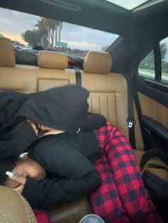 two people sitting in the back seat of a car with their heads covered by blankets