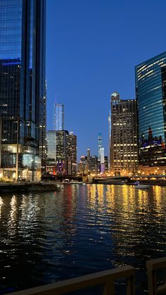 the city is lit up at night by the water's edge and reflecting its lights