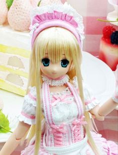 a doll sitting on top of a table next to a plate with cake in the background