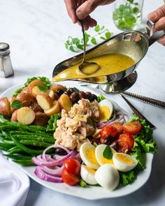 a person pouring dressing over a plate of food