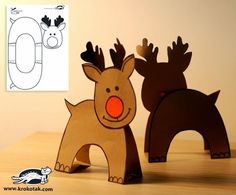 two paper reindeer standing next to each other on top of a wooden table with an orange nose