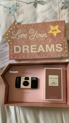 a pink box with a camera inside and some writing on the side that says live your dreams