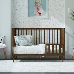 a white cat sitting on top of a wooden crib next to a wall with flowers