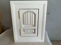 a white door with a gold handle on top of a table next to a wall