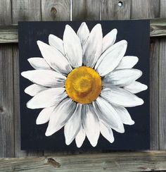 a painting of a white and yellow flower on a black background with wood planks