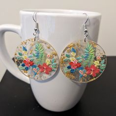 These delightful tropical earrings are made with lightweight circular resin pendants that are transparent with gold foil flecks, and nickel-free ear wires. Dangle length is approximately 1.5 inches, not including ear wires. To extend the life of your earrings, avoid contact with sweat, lotions, and other chemicals. Please message me with any questions. To see other jewelry options, check out my full store: https://www.etsy.com/shop/shopcraftyoctopus/ Summer Gold Resin Earrings, Round Resin Flower Earrings, Gold Round Resin Flower Earrings, Gold Round Flower Earrings In Resin, Flower Transparent, Tropical Earrings, Resin Pendants, Gold Flecks, Tropical Flower