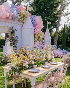 a table set up for a princess party with balloons and flowers on the wall behind it