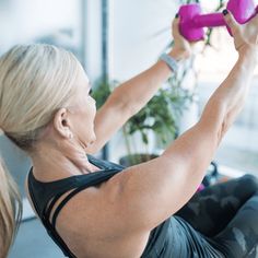 a woman doing exercises with pink dumbbells