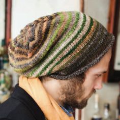 a man with a beard wearing a knitted hat and scarf in front of a bar