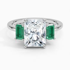 an emerald and diamond ring with three stone accents