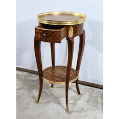 an antique side table with two drawers and gold trimmings on the bottom shelf