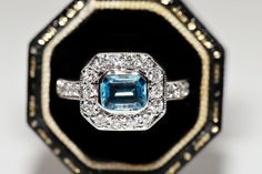 an engagement ring with a blue topaz surrounded by white and yellow gold trimmings