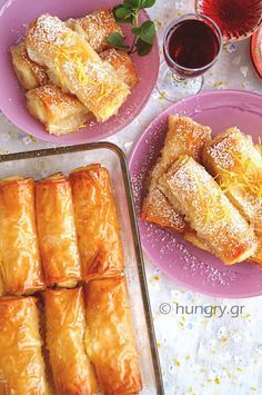 pastries on pink plates next to two glasses of red wine