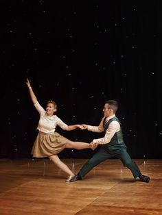 two people are dancing on a stage with stars in the sky and one person is wearing a dress