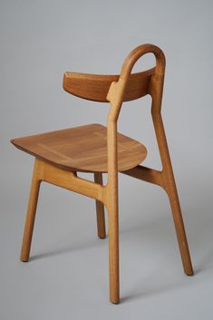 a wooden chair on a grey background with the seat up and arm extended to the side