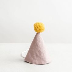 a small pink cone with yellow pom - poms on it's top