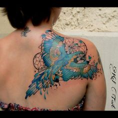 the back of a woman's shoulder with a colorful bird tattoo on her upper arm