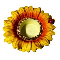 a sunflower shaped vase with a ladybug sitting on it's side