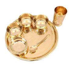 a gold plate with cups and spoons on it