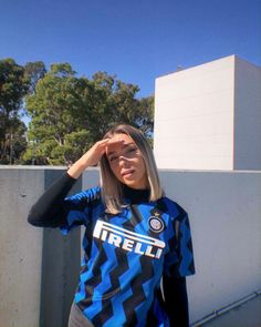 a woman in a blue and black striped shirt is holding her hand up to her head