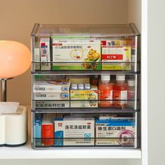 an assortment of medicine and other medical supplies on a shelf next to a table lamp