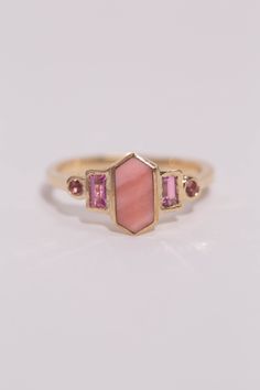 Art deco inspired ring featuring pink opal, tourmaline, and sapphires. The opaque centerstone is Australian pink opal, with streaking shades of soft pink. The pink opal is inlaid into the elongated hexagon, measuring 9.5mm x 5mm. Light pink sapphire baguettes are at the sides, accented by brilliant cut pink tourmaline. Millimeter measurement from end to end is 15mm. Your choice of gold color and karat. Band is 1.75mm thick. Please leave a note at checkout with your preferred size. All gems and r Pink Opal Ring, Pink Engagement Ring, All Gems, Custom Ring Designs, Pink Gemstones, Mirror Mirror, Art Deco Inspired, Recycled Gold, Pink Opal