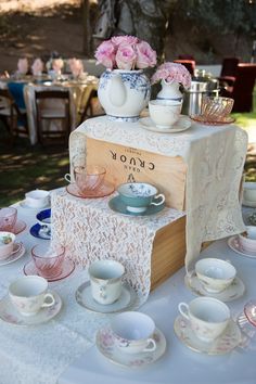 a table topped with lots of tea cups and saucers next to a wooden box