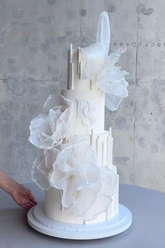 a woman is decorating a white wedding cake with flowers on the top and sides