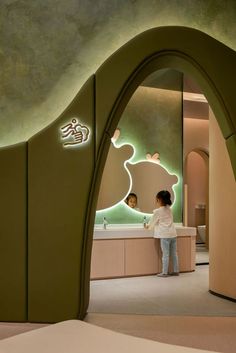 two people standing in front of a bathroom with green walls and lights on the wall