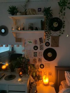 a bedroom with candles, pictures and plants on the wall next to a bed in front of a window