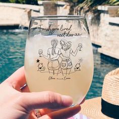 a person holding up a wine glass in front of a swimming pool with two women drawn on it