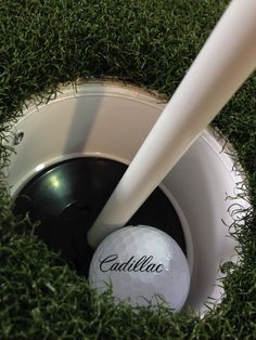 a golf ball is in the hole with a white tee sticking out of it's side