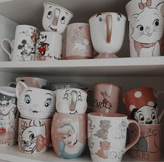 many disney mugs are lined up on the shelf