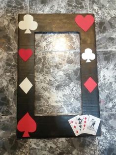 a picture frame with playing cards and hearts on the inside, sitting on a tile floor