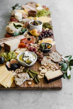 a wooden board topped with lots of different types of cheese and crackers on top of it