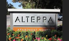 a sign that says alterra apartment homes in front of some flowers