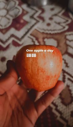 someone holding an orange with the words one apple a day on it