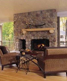 a living room filled with furniture and a fire place in front of a stone fireplace