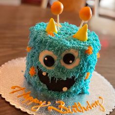 a birthday cake with blue frosting and orange sprinkles that looks like a monster