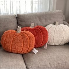 three pumpkin pillows sitting on top of a gray couch next to a white and orange pillow