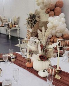 the table is set with white and brown decorations, candles, and pumpkins on it