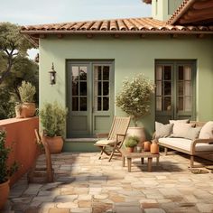 a patio with chairs, tables and potted plants in front of a green house