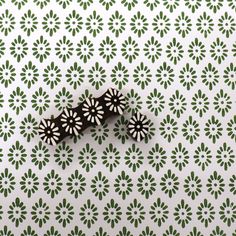 two pieces of black and white paper sitting on top of a green and white wallpaper