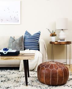 a living room filled with furniture and pillows on top of a white rug covered floor