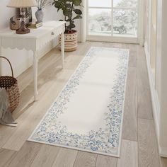 a white rug with blue flowers on it in front of a window next to a lamp